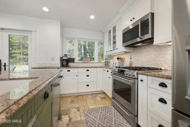 a kitchen with stainless steel appliances granite countertop a stove a sink and a microwave