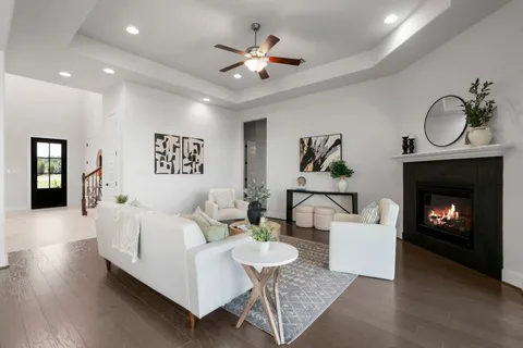 a living room with furniture a fireplace and a ceiling fan