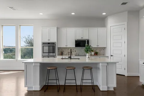 a kitchen with stainless steel appliances a dining table chairs microwave and cabinets