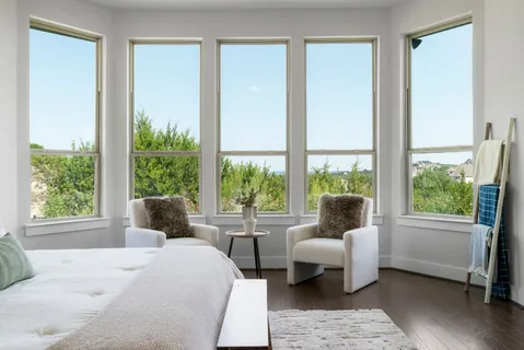 a bedroom with a bed and large windows