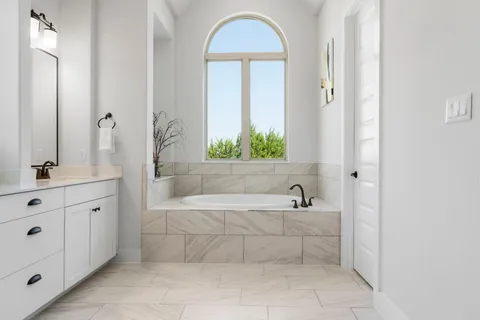 a bathroom with a tub a sink and a window