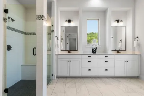 a bathroom with double vanity sink a mirror a window and glass door