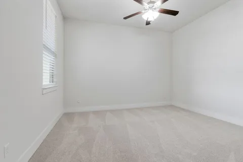 an empty room with a window and a fan