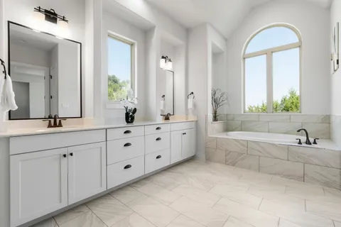 a bathroom with a double vanity sink mirror and bathtub