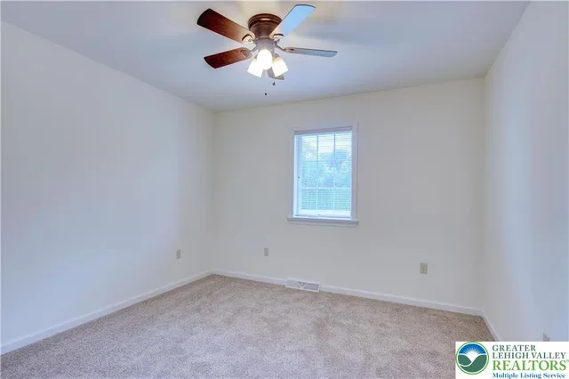 an empty room with a window and a fan