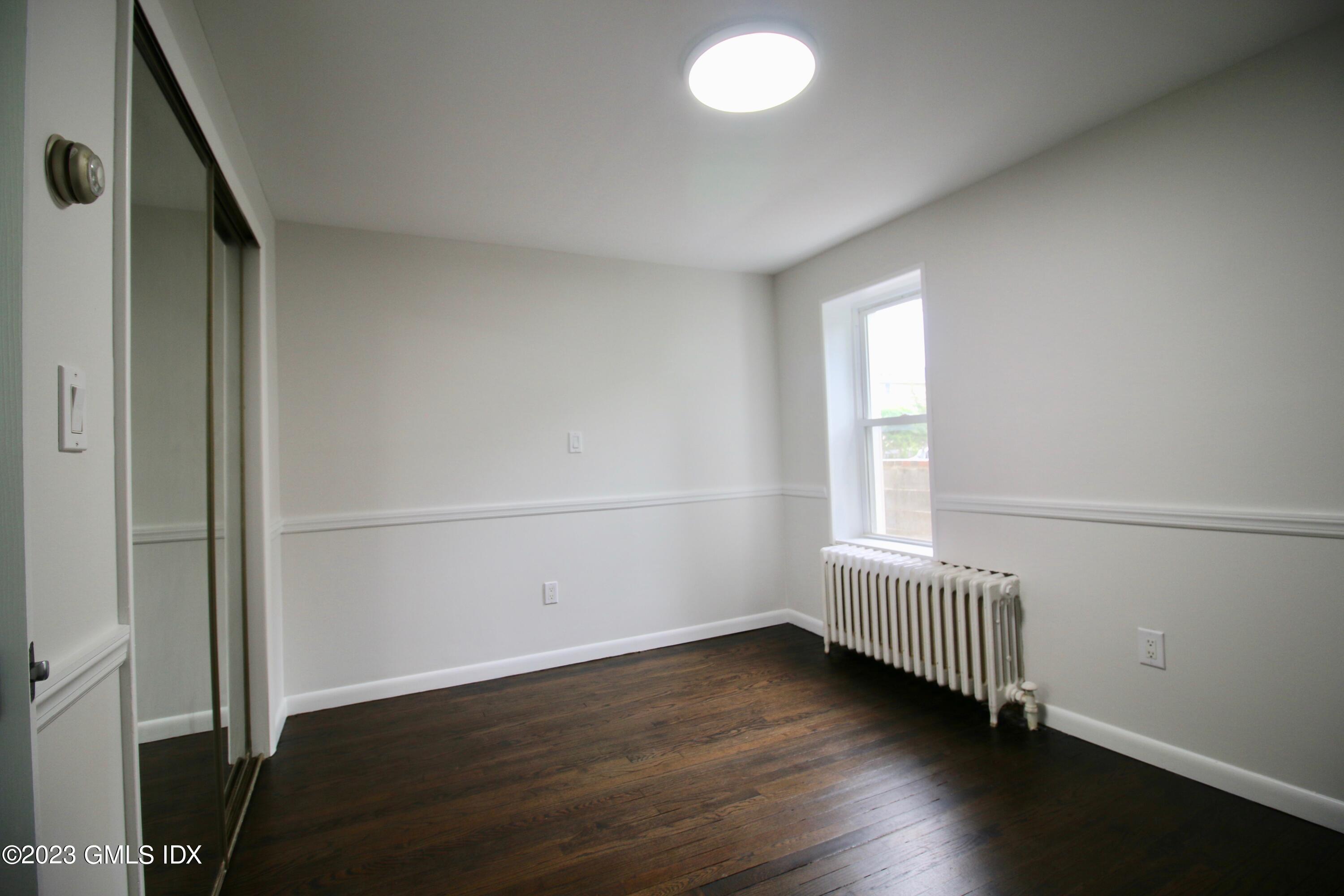 25 Bible Street, Unit 1 Cos Cob, CT 06807 - Photo 8 of 12 an empty room with wooden floor and windows