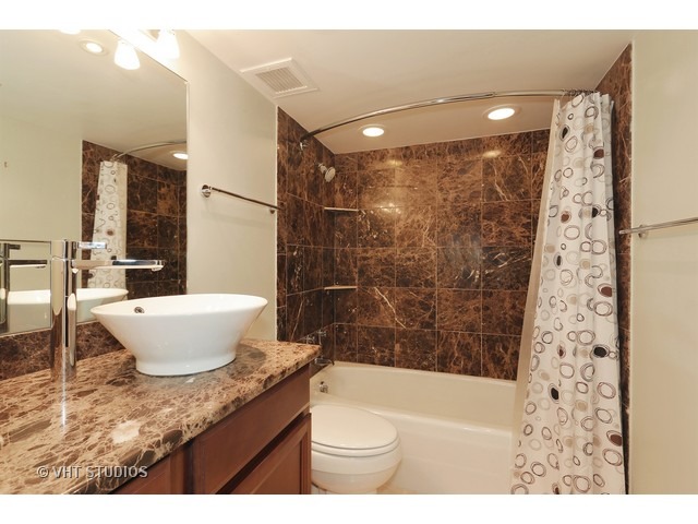 175 East Delaware Place, Unit 6001 Chicago, IL 60611 - Photo 7 of 10 a bathroom with a granite countertop sink toilet a mirror a bathtub and shower