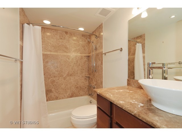 175 East Delaware Place, Unit 6001 Chicago, IL 60611 - Photo 9 of 10 a bathroom with a granite countertop sink a toilet a mirror and shower