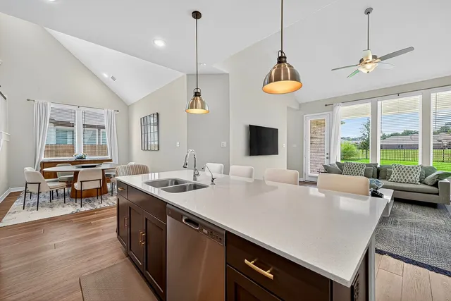 a kitchen with stainless steel appliances granite countertop a sink a stove and a wooden floor
