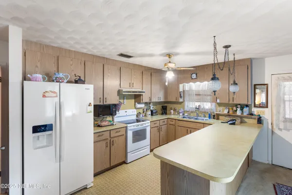 a kitchen with refrigerator a sink a stove and chairs with wooden floor