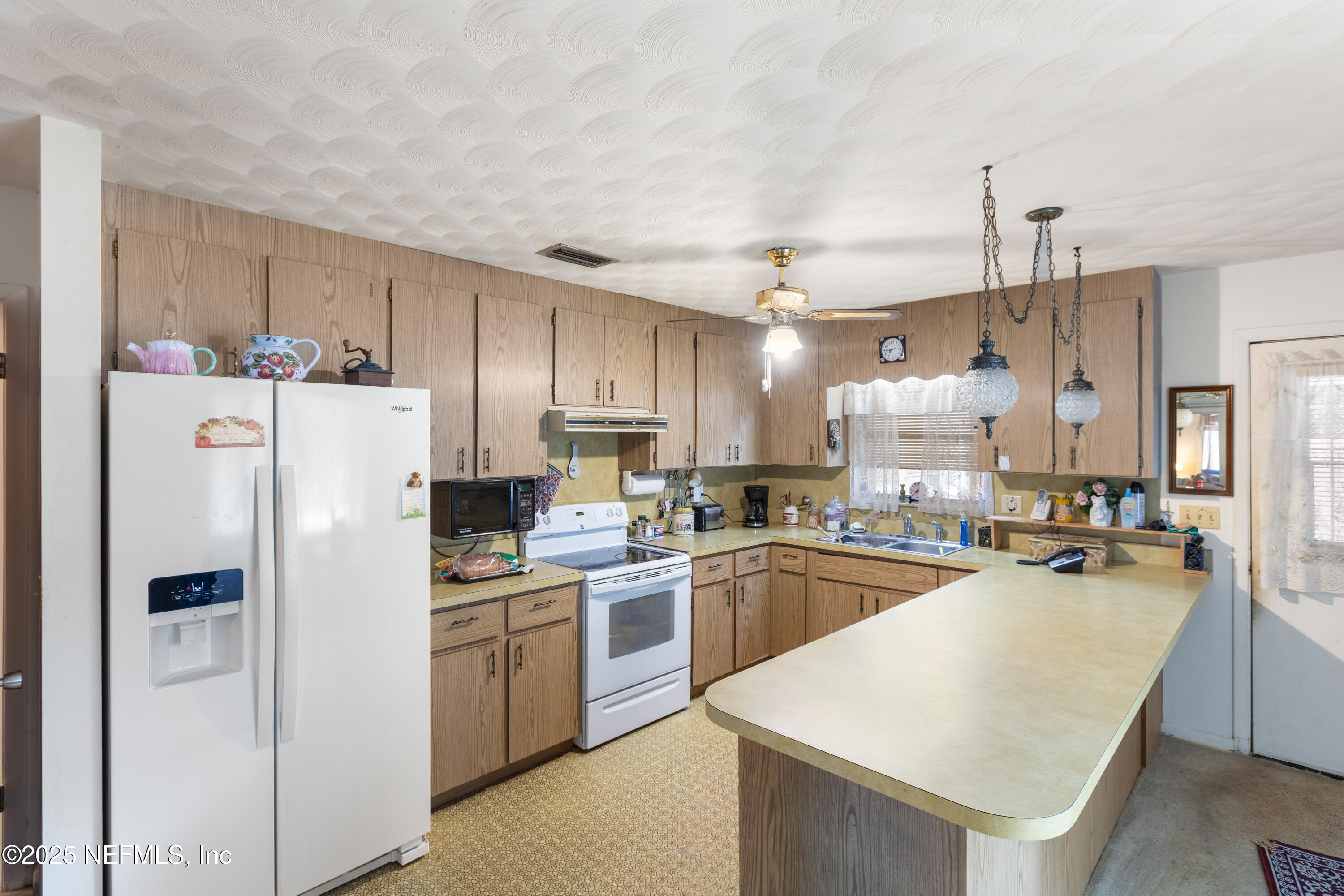 6276 Magnolia Street Keystone Heights, FL 32656 - Photo 10 of 45 a kitchen with refrigerator a sink a stove and chairs with wooden floor