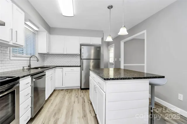 a kitchen with granite countertop a sink and refrigerator