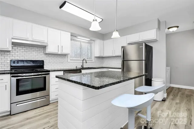 a kitchen with granite countertop a stove sink and refrigerator