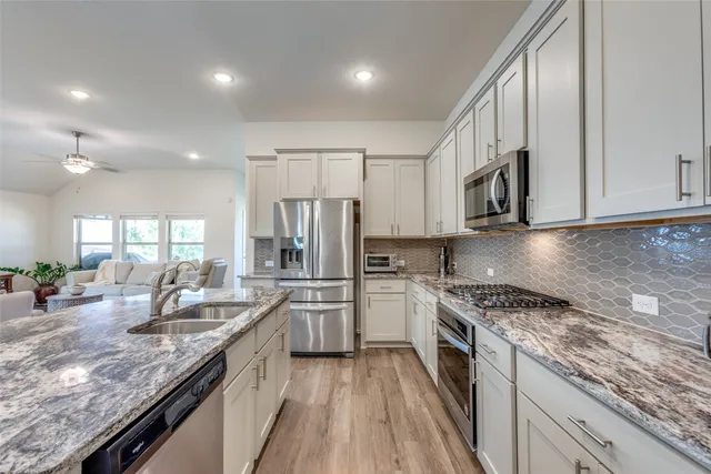 a kitchen with stainless steel appliances granite countertop a sink stove and refrigerator