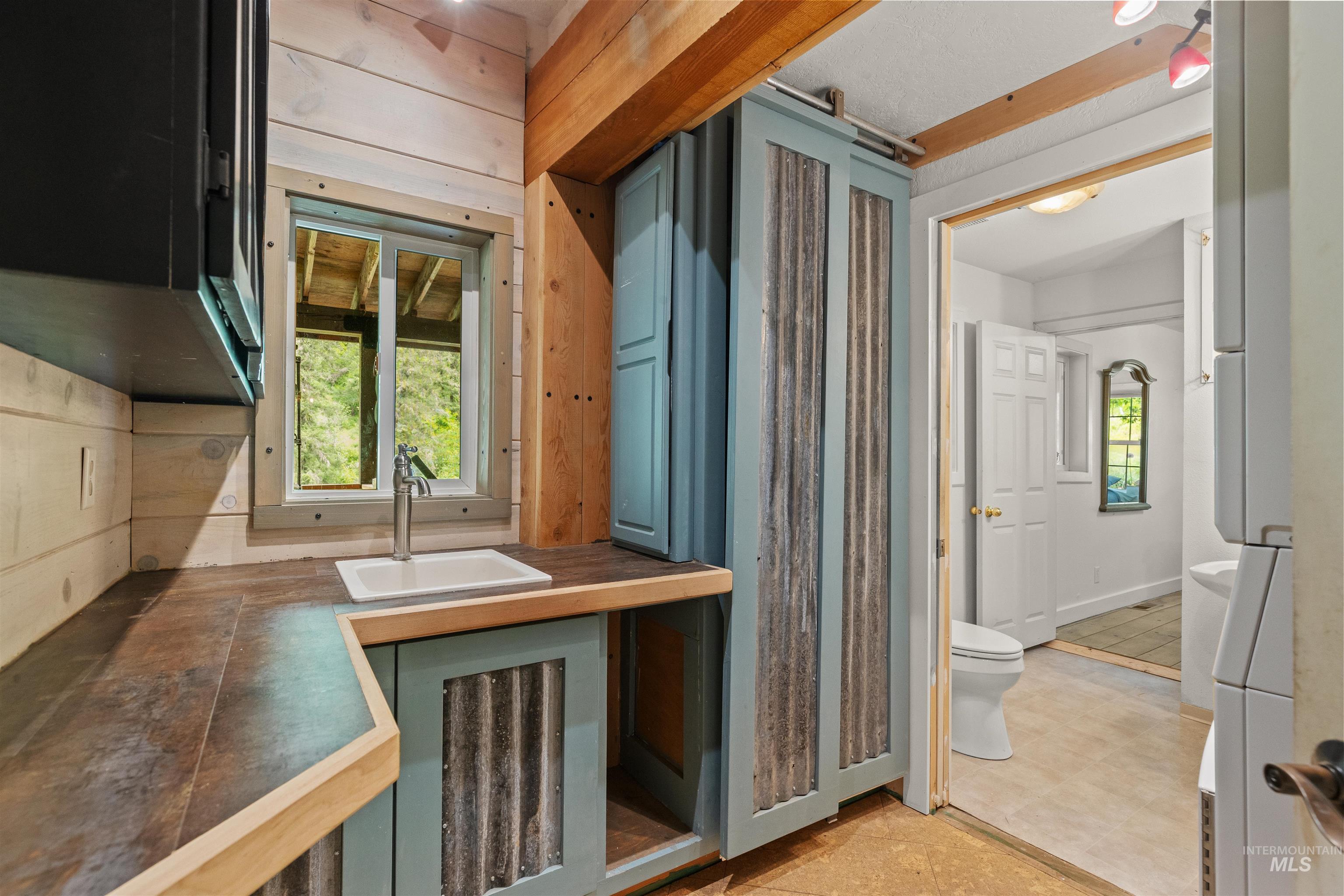 1314 Cedar Ridge Road Kendrick, ID 83537 - Photo 17 of 50 Kitchenette featuring a white sink basin, a window with exterior visibility, and corrugated metal cabinet accents