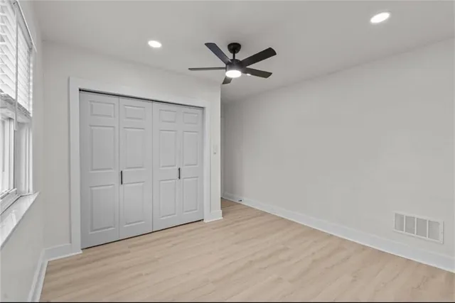 an empty room with a ceiling fan and window