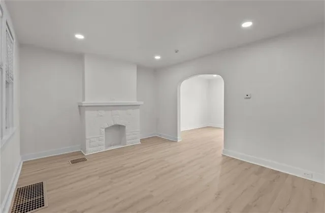a view of an empty room with wooden floor and a fireplace