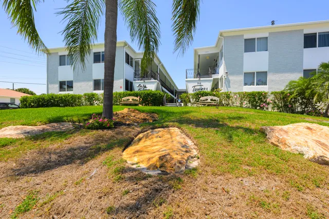 a view of a house with a yard and palm trees