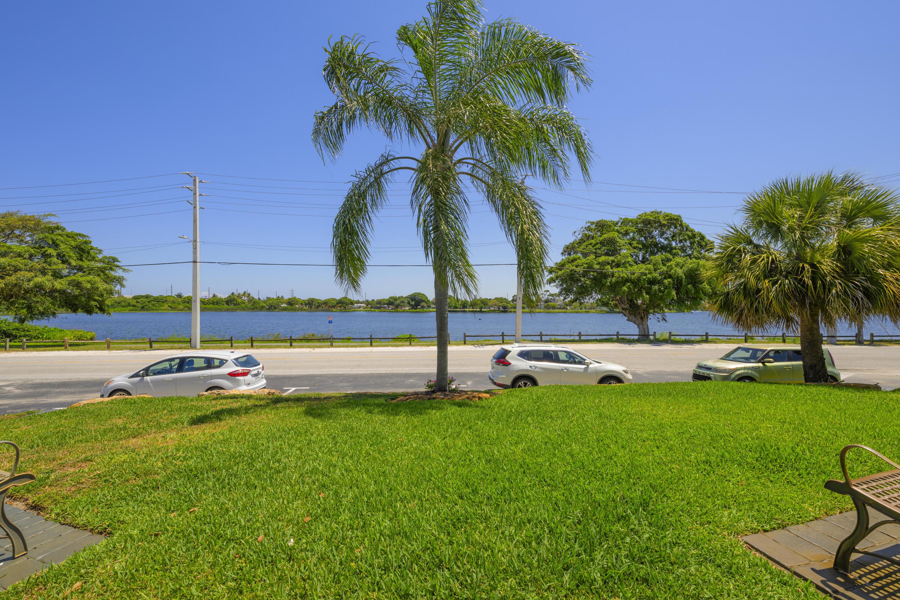 302 Lake Osborne Drive, Unit 4 Lake Worth Beach, FL 33461 - Photo 4 of 10 a view of a swimming pool with a garden and palm trees
