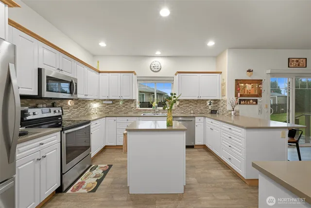 a kitchen with kitchen island granite countertop stainless steel appliances cabinets a sink and a counter top space
