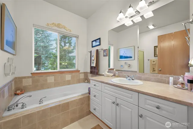 a bathroom with a tub a sink double vanity and a mirror