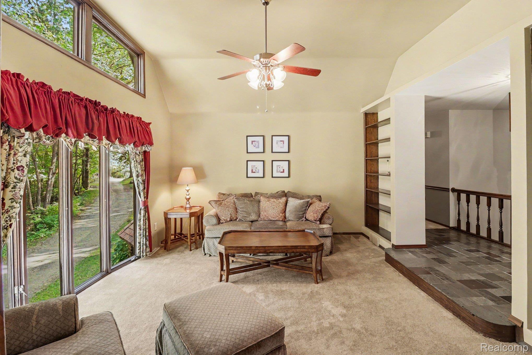 6300 North Raddatz Road Fowlerville, MI 48836 - Photo 16 of 42 Vaulted ceiling with a ceiling fan, built-in shelving, large sliding glass doors, transom windows, and tile flooring at entry