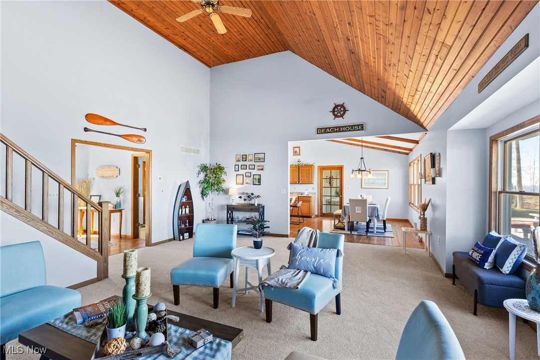 1122 Lake Road Conneaut, OH 44030 - Photo 28 of 50 Carpeted living room featuring high vaulted ceiling, wooden ceiling, stairway, ceiling fan with notable chandelier, and visible vents