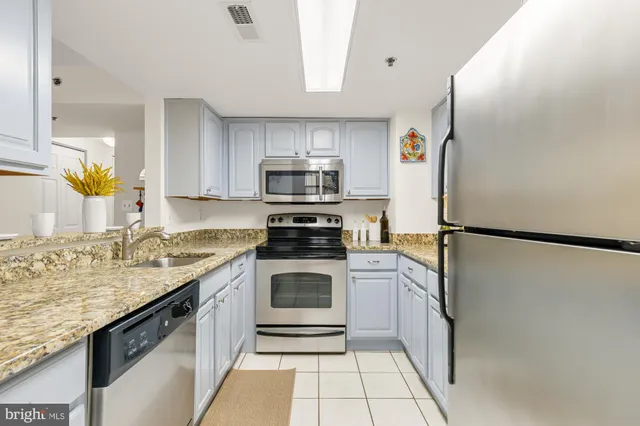 a kitchen with granite countertop white cabinets stainless steel appliances and a sink