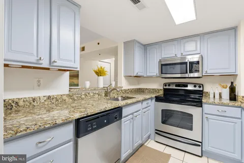 a kitchen with granite countertop cabinets stainless steel appliances and a counter space