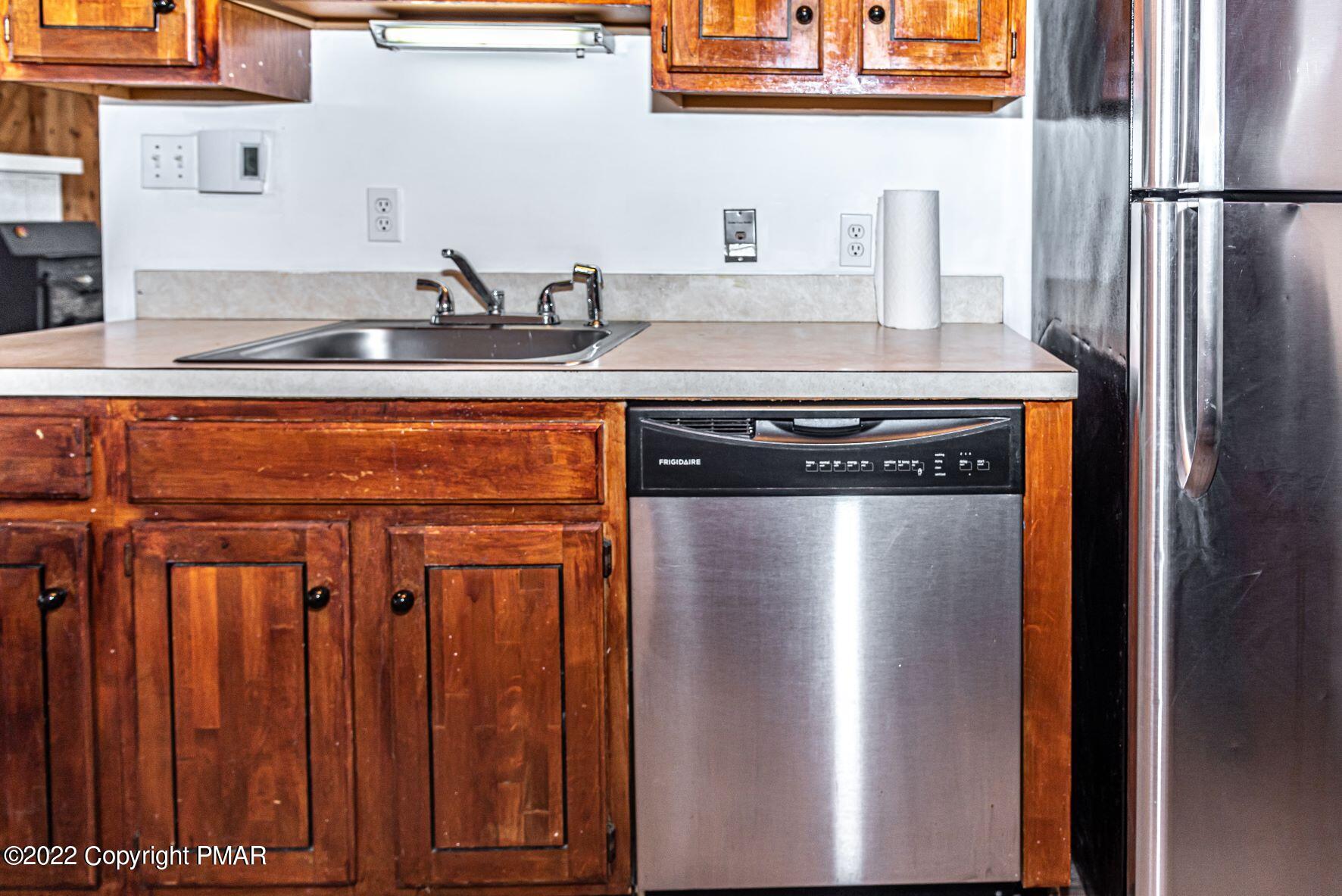 250 Canterbury Road Bushkill, PA 18324 - Photo 15 of 39 a close view of kitchen counter with stainless steel appliances granite countertop a refrigerator a sink and wooden cabinets