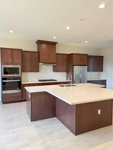 a large kitchen with kitchen island a sink stainless steel appliances and cabinets