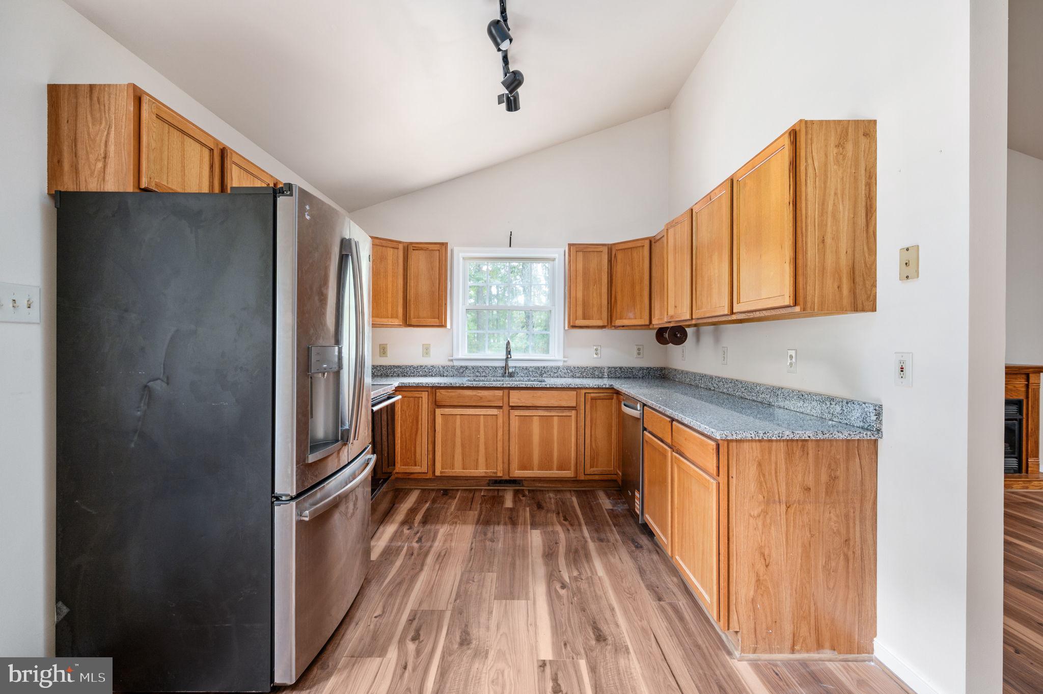 1822 Copper Line Road Bumpass, VA 23024 - Photo 21 of 65 a kitchen with granite countertop wooden cabinets a sink a window and stainless steel appliances