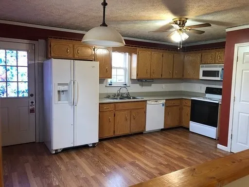 a kitchen with stainless steel appliances granite countertop a sink a stove a refrigerator cabinets and wooden floor