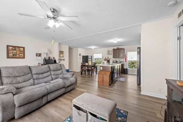a living room with furniture kitchen view and a wooden floor