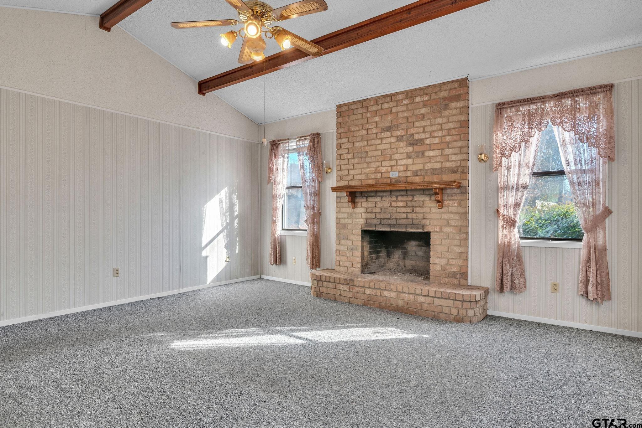501 Samuel Street Marshall, TX 75672 - Photo 19 of 41 a view of a livingroom with a fireplace a ceiling fan and windows