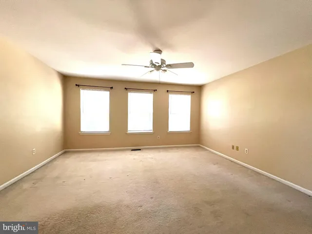 an empty room with a window and a ceiling fan