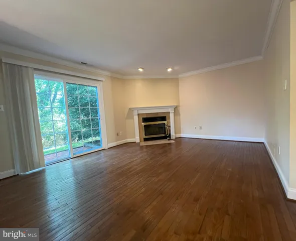 an empty room with wooden floor fireplace and windows
