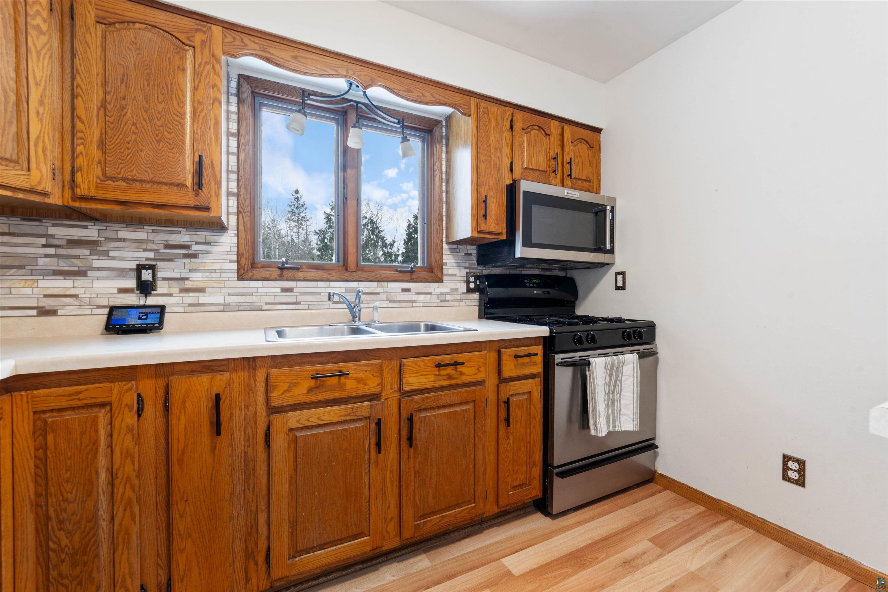 6949 County Rd A Superior, WI 54880 - Photo 7 of 34 Kitchen featuring sink, backsplash, light hardwood / wood-style flooring, and gas range oven