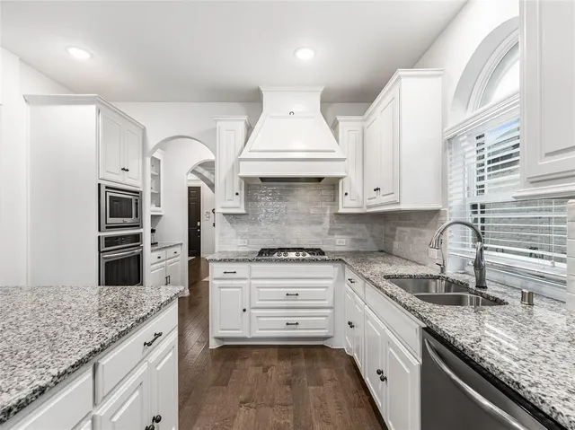 a kitchen with granite countertop a sink stainless steel appliances and cabinets