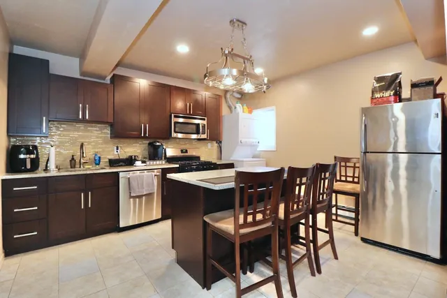 a kitchen with stainless steel appliances granite countertop wooden cabinets a dining table and chairs