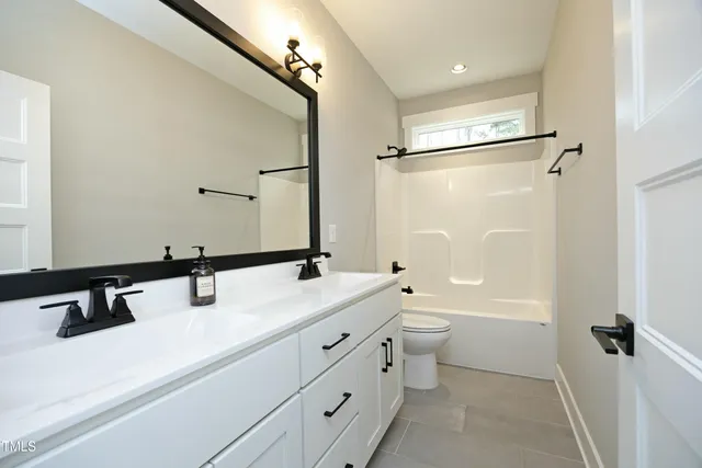 a bathroom with a double vanity sink toilet mirror and bathtub