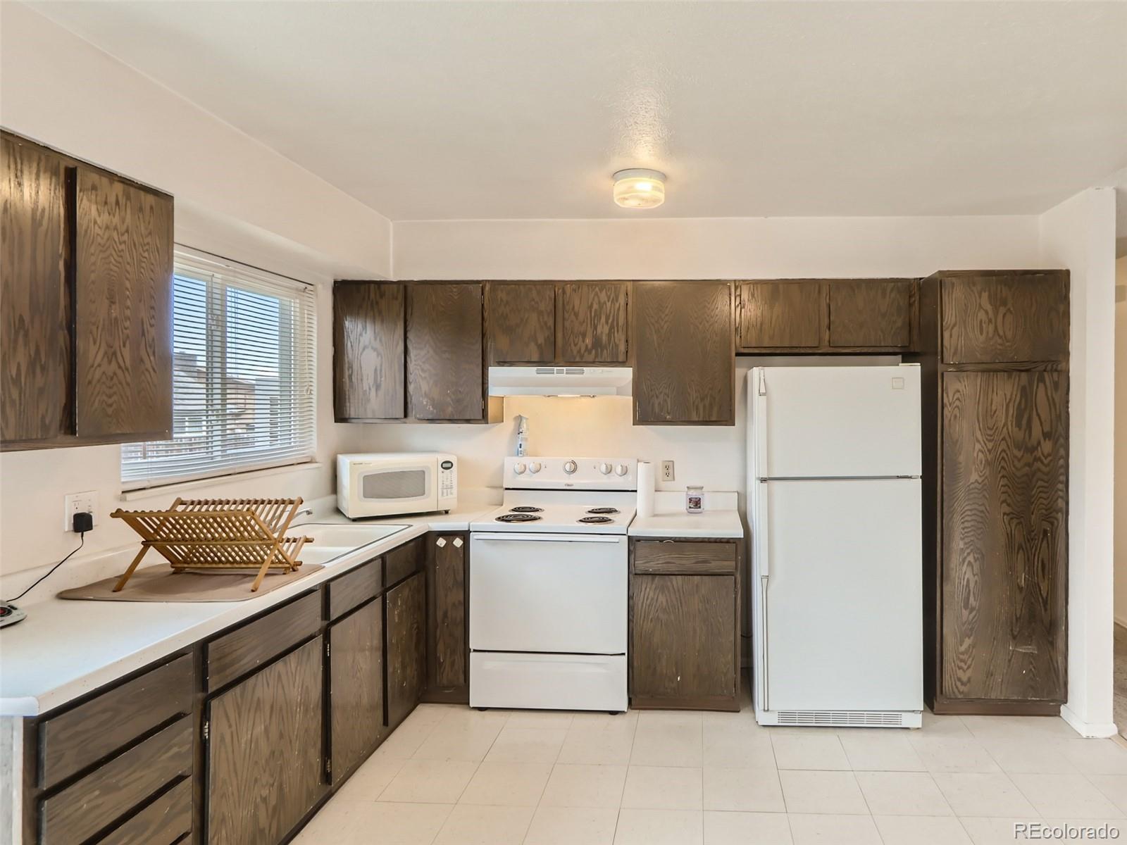 1632 South Rifle Street Aurora, CO 80017 - Photo 14 of 26 a kitchen with a sink a stove a refrigerator and cabinets