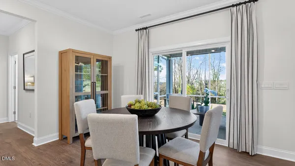 a kitchen with stainless steel appliances granite countertop a stove a refrigerator a sink a dining table and chairs with wooden floor