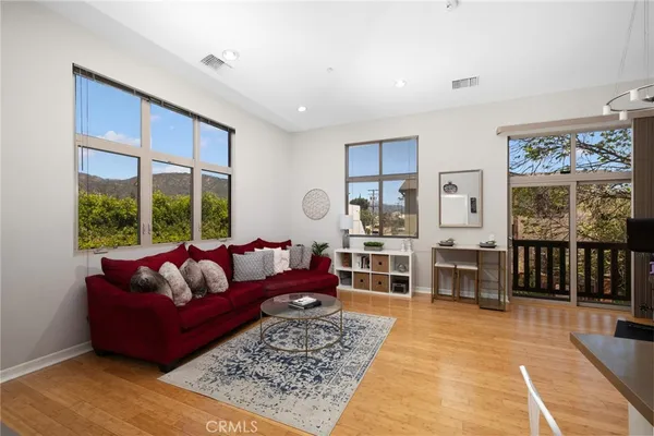 a living room with furniture large windows and wooden floor