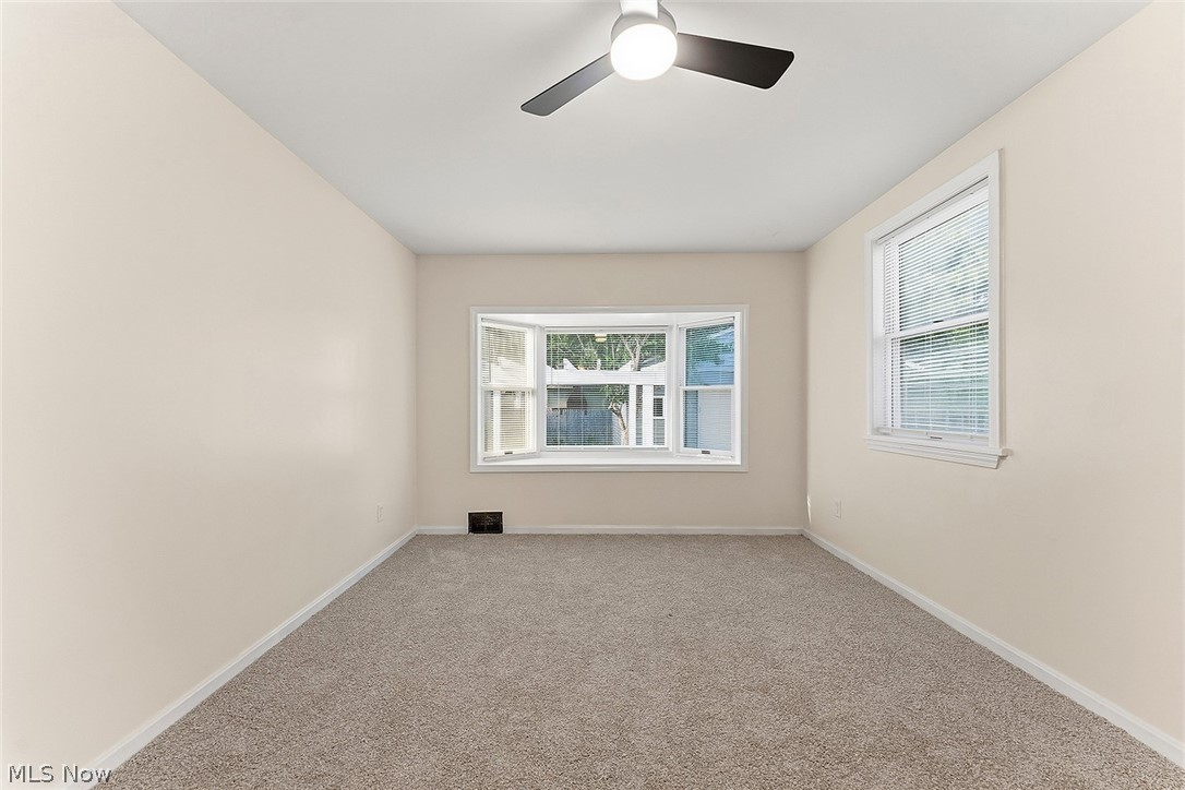 3791 Fairoaks Road South Euclid, OH 44121 - Photo 14 of 30 Carpeted interior room featuring a bay window, a standard window, a ceiling fan with integrated lighting, and neutral-toned walls