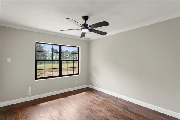 a view of an empty room with a window and wooden floor