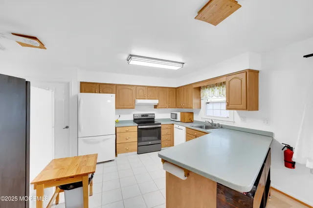 a kitchen with a refrigerator a stove top oven a sink dishwasher and white cabinets with wooden floor