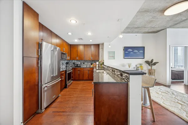 a large kitchen with stainless steel appliances granite countertop a lot of counter space and wooden floors