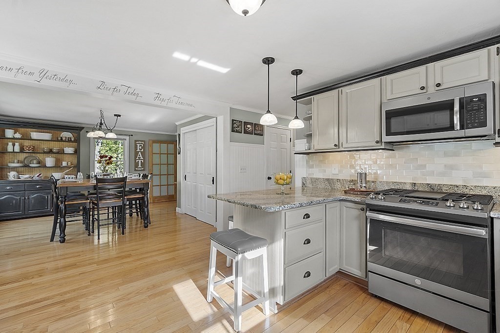 264 Hackett Hill Road Hooksett, NH 03106 - Photo 5 of 41 a kitchen with stainless steel appliances granite countertop a stove top oven a sink dishwasher a dining table and chairs with wooden floor