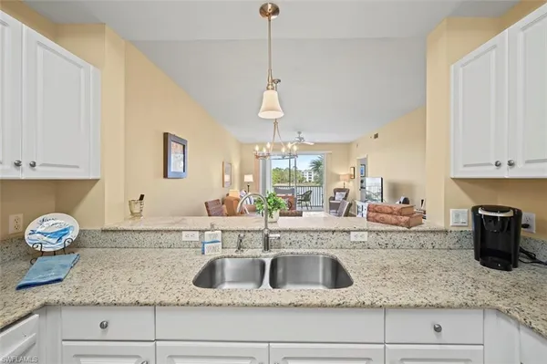 a kitchen with granite countertop a sink a stove and cabinets